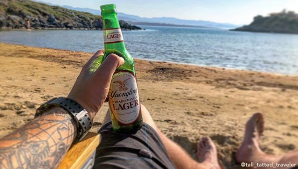 A fan photo holding a Yuengling on a beach